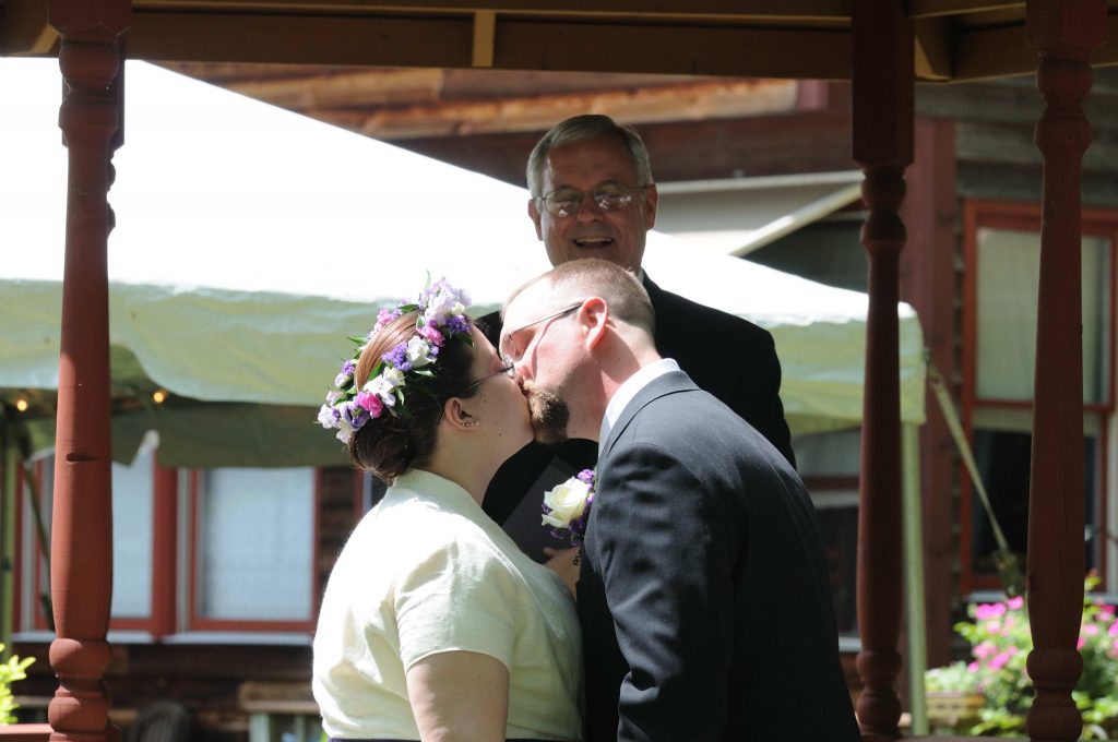 Bride and groom kiss in front of officiant