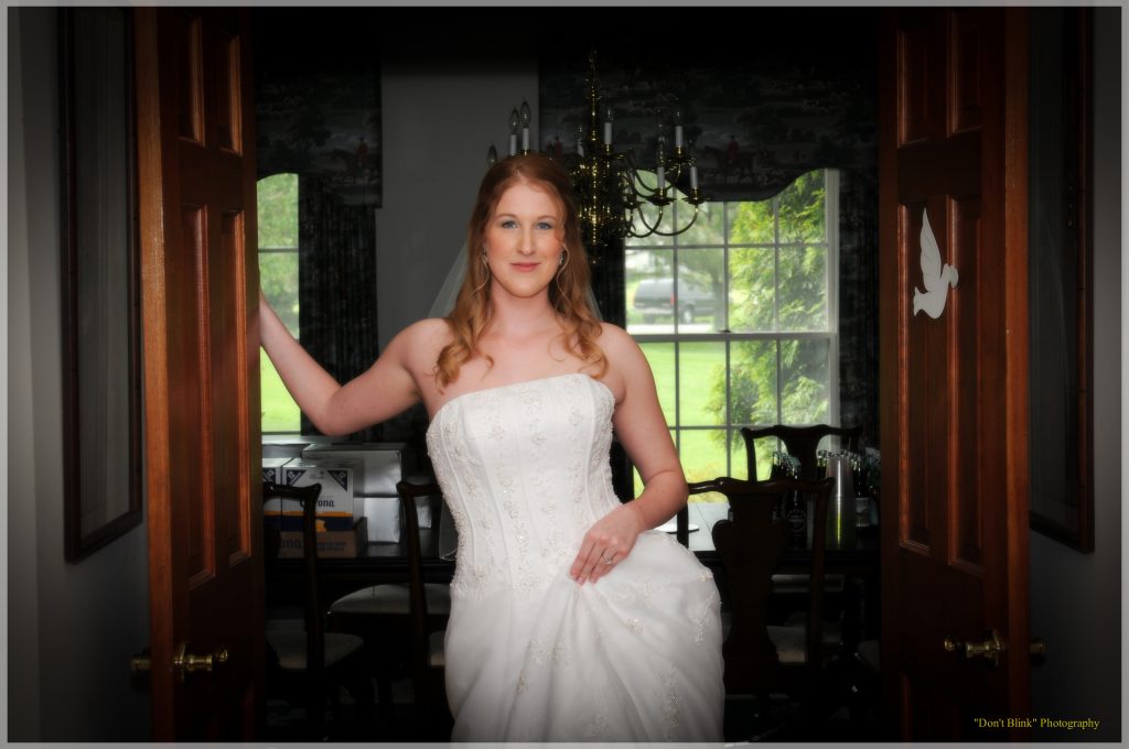 A bride with red hair stands in a doorway