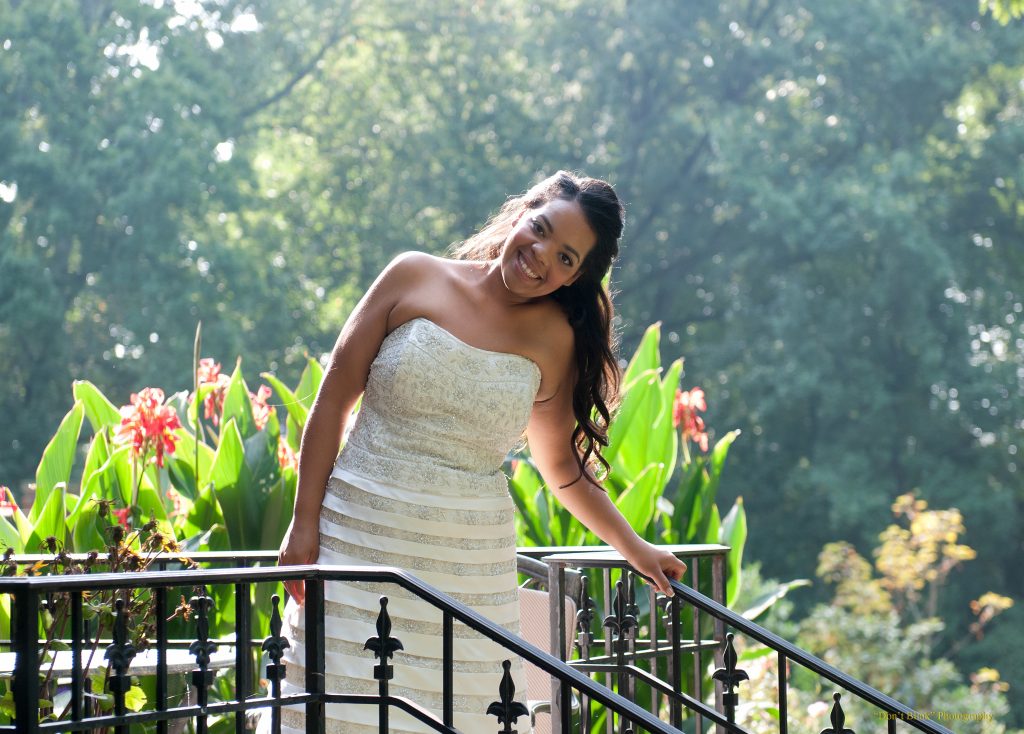 Woman in white dress leans on a wooden railing