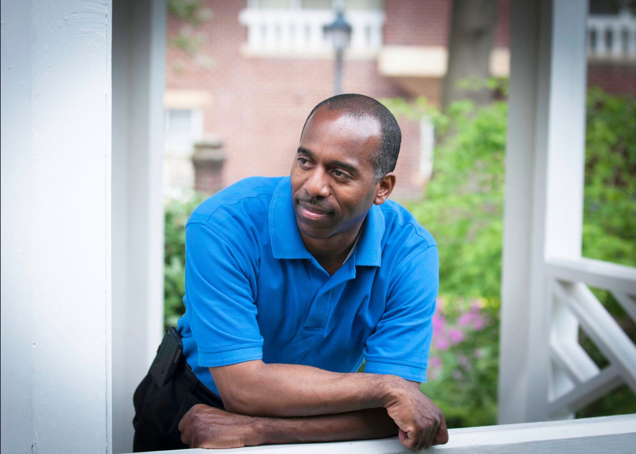 Jeffrey in a blue polo leaning on a white wooden railing